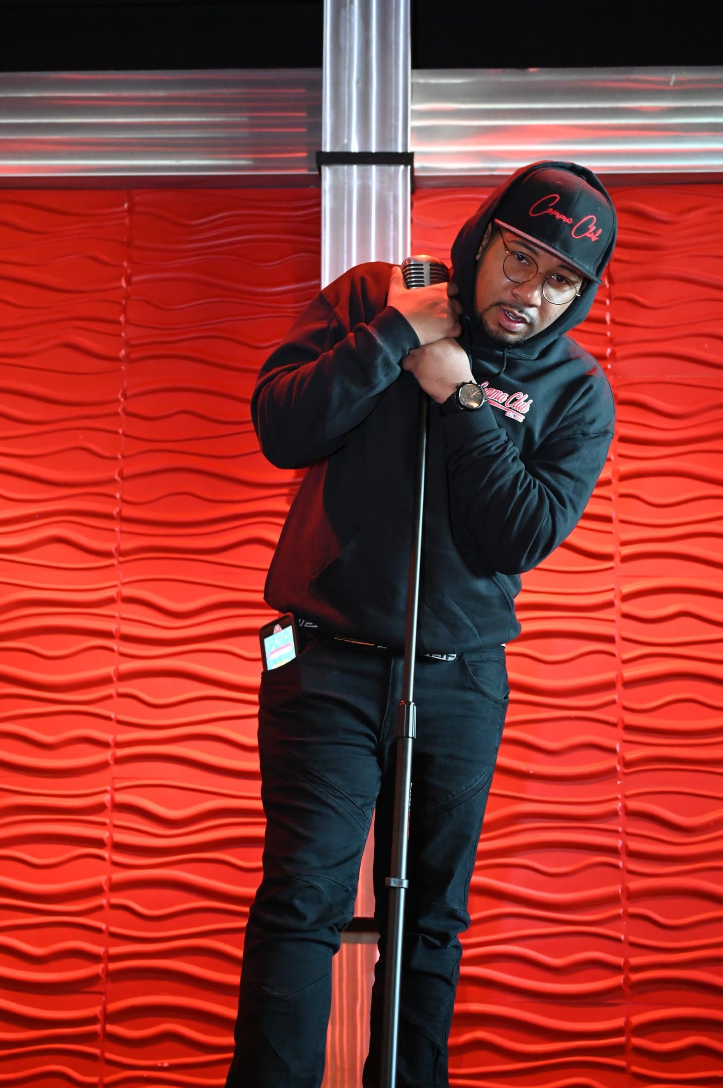 Wesley Robinson performing in a hat against a red stage wall